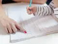 Dziecko ćwiczy pisanie, a dorosły pokazuje mu ćwiczenia grafomotoryczne klasa 1.