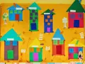 Kolorowa praca plastyczna z figur geometrycznych przedstawia wioskę z domkami.