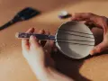 Ręce składają proste instrumenty muzyczne do zrobienia: miseczkę z gumkami i patyczek.