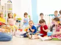 Wesołe zabawy w przedszkolu: dzieci grają na instrumentach, śpiewają i bawią się z nauczycielem.