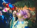 Szampańskie zabawy na imprezie! Mężczyzna nalewa alkohol prosto do ust przyjaciela, obaj uśmiechnięci i pełni radości.
