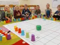 Dzieci uczą się kodowania dla przedszkolaków, bawiąc się kolorowymi kubeczkami i planszą z kostką.