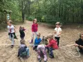 Dzieci biorą udział w leśnej grze terenowej, przeciągając linę.