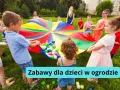 Radosne zabawy dla dzieci w ogrodzie z kolorowym spadochronem i piłeczkami. Dzieci śmieją się, trzymając materiał, tworząc falę.