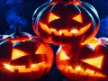 Trzy świecące **jack o lantern** z wyciętymi strasznymi minami, otoczone niebieską mgłą, tworzą mroczny, halloweenowy nastrój.
