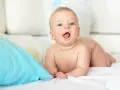 Niebieskooki bobas na brzuchu, kiedy dziecko głuży, z otwartymi ustami i radosnym wyrazem twarzy.