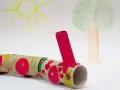 Kolorowy pociąg z rolek po papierze toaletowym, wykonany z rzeczy z recyklingu dla dzieci. W tle rysunek słońca i drzewa.