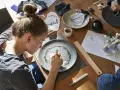 Dziewczyna maluje wzór na talerzu, tworząc własny przepis na masę porcelanową.