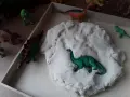 Zabawy z masą plastyczną i figurkami dinozaurów to świetne pomysły na dzień dinozaura. Dzieci mogą tworzyć prehistoryczne krajobrazy.