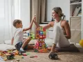 Mama i syn świętują sukces budowli z klocków magnetycznych. To świetne kreatywne zabawy dla 8 latka, rozwijające wyobraźnię i zdolności manualne.