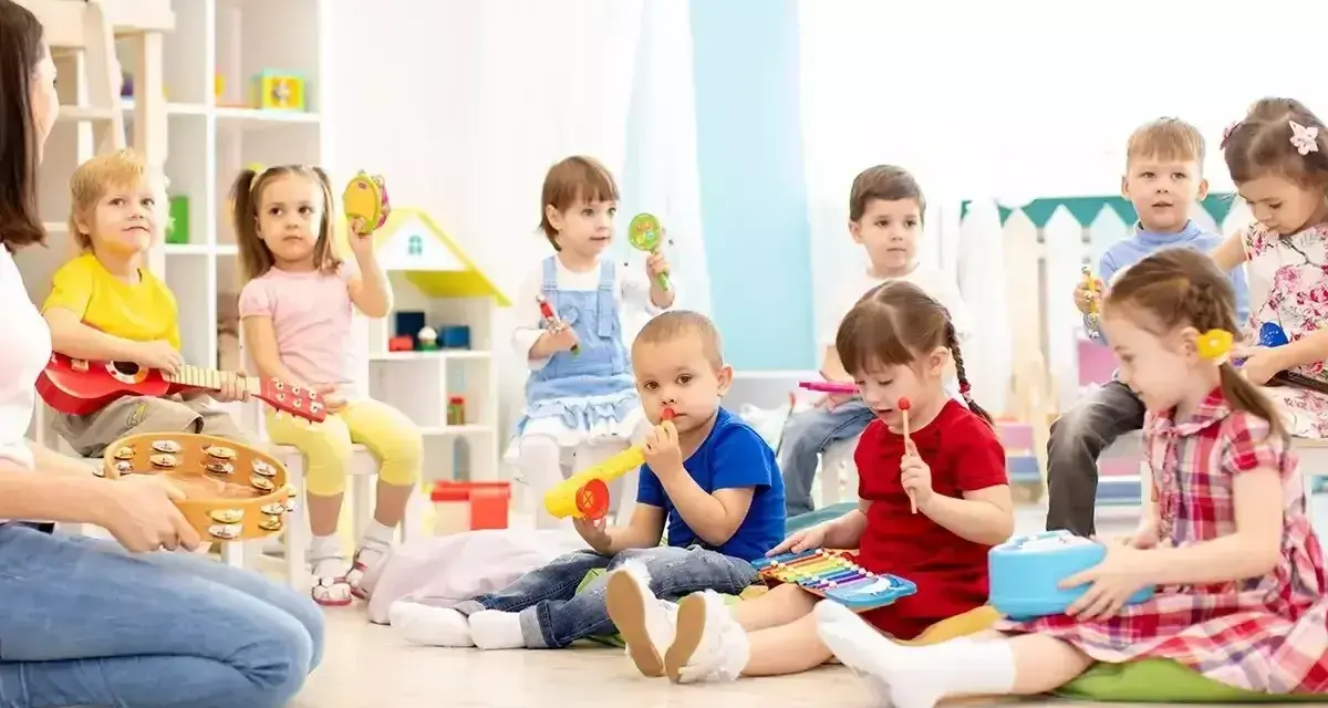 Wesołe zabawy w przedszkolu: dzieci grają na instrumentach, śpiewają i bawią się z nauczycielem.