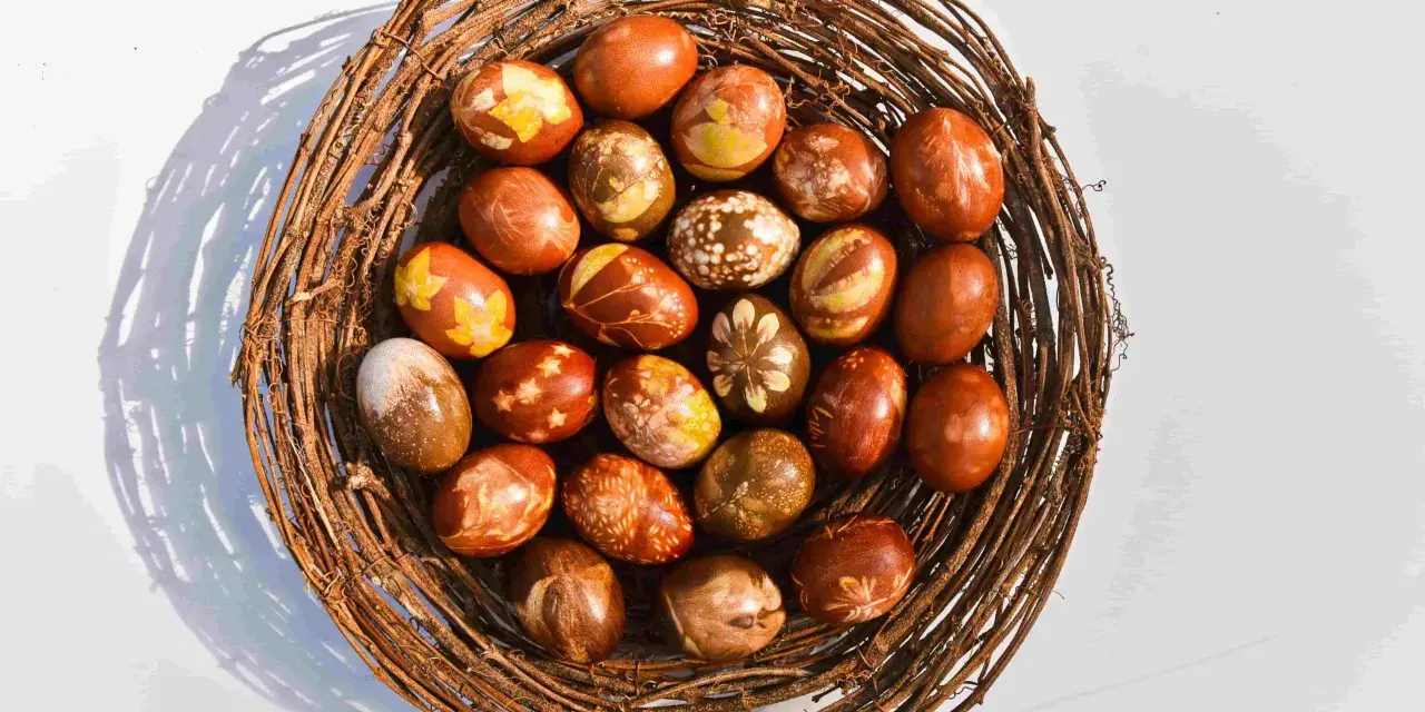 Wielkanocne pisanki w koszyku z gałęzi, barwione w łuskach cebuli, z naturalnymi wzorami liści i kwiatów.