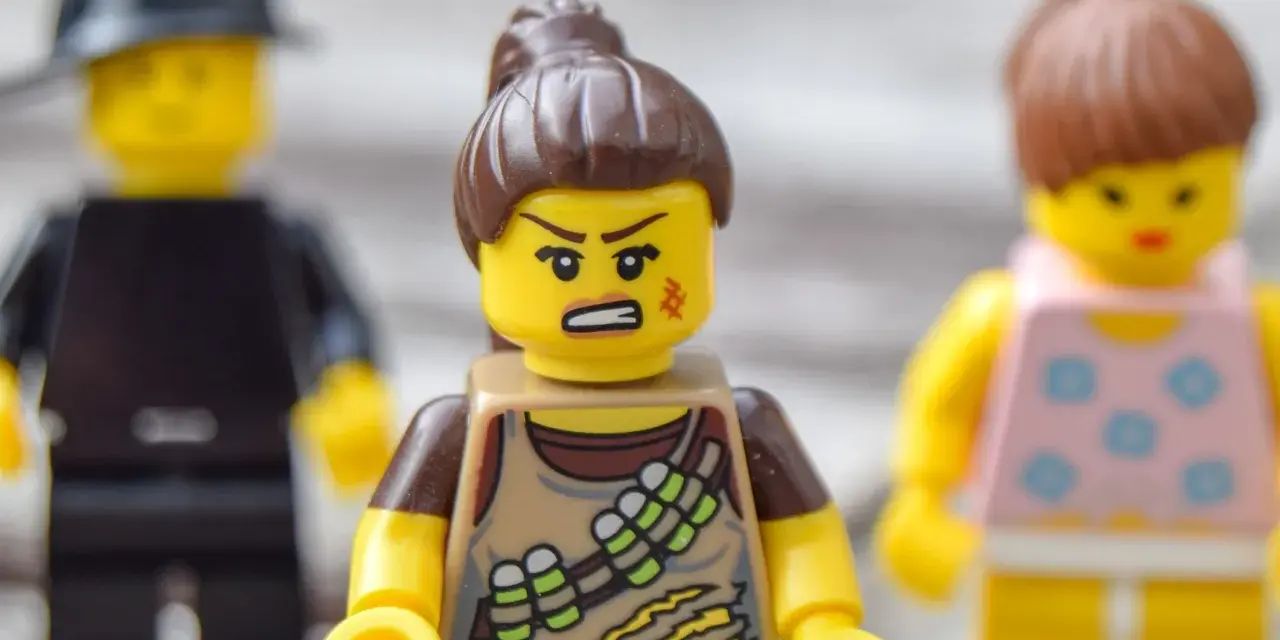 Trzy ludziki Lego. Jeden z nich, w brązowym stroju, ma zaciętą minę, co sugeruje nieradzenie sobie z emocjami.