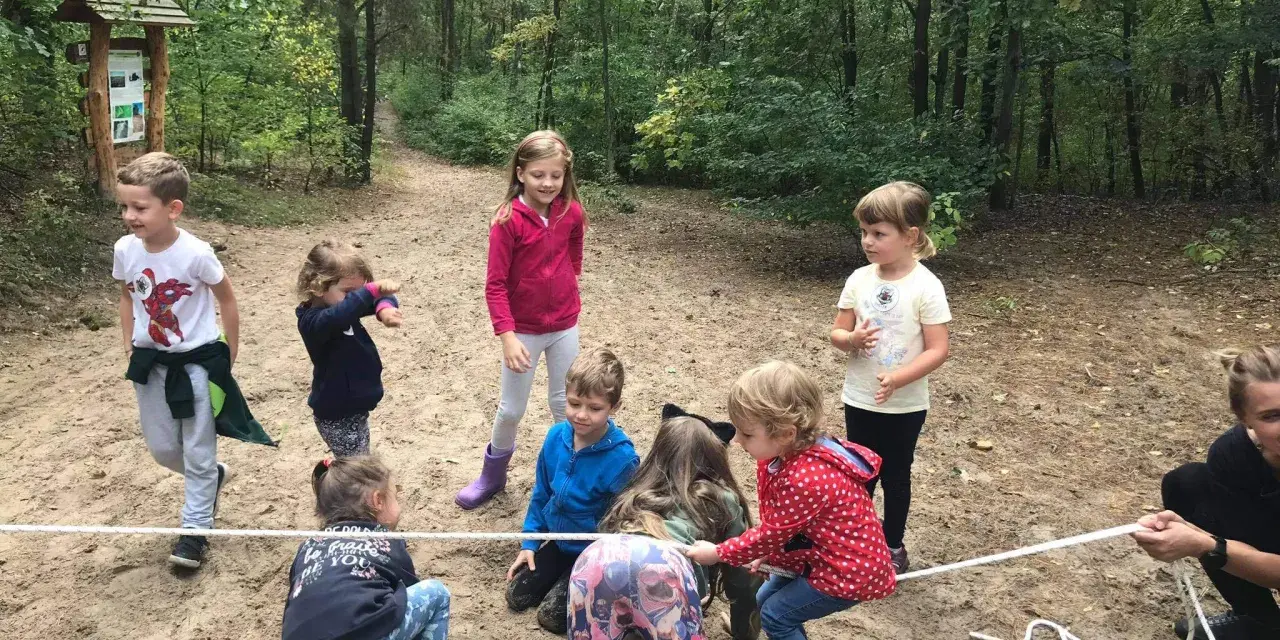 Dzieci biorą udział w leśnej grze terenowej, przeciągając linę.
