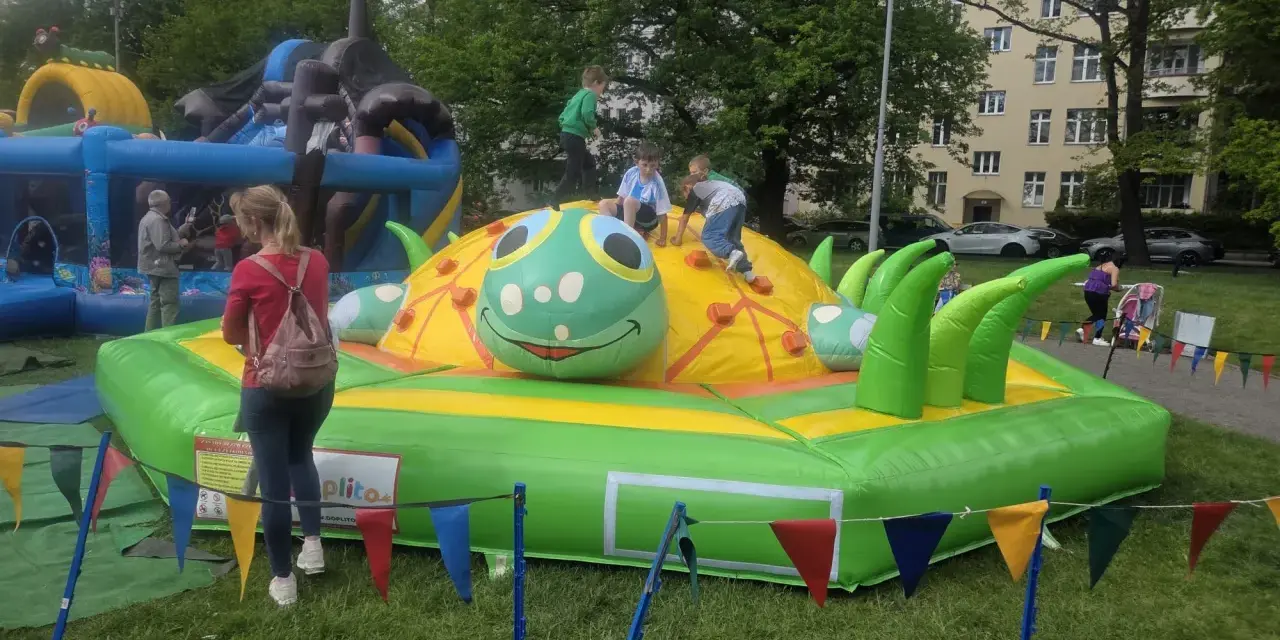 Dzieci bawią się na dmuchanej gąsienicy, która jest jedną z atrakcji na dzień dziecka.