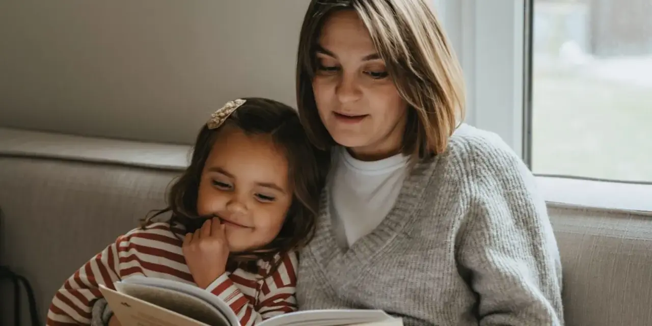 Mama czyta dziecku bajkę, pokazując, jak zachęcić dziecko do czytania. Wspólne chwile z książką budują więź i rozwijają wyobraźnię.