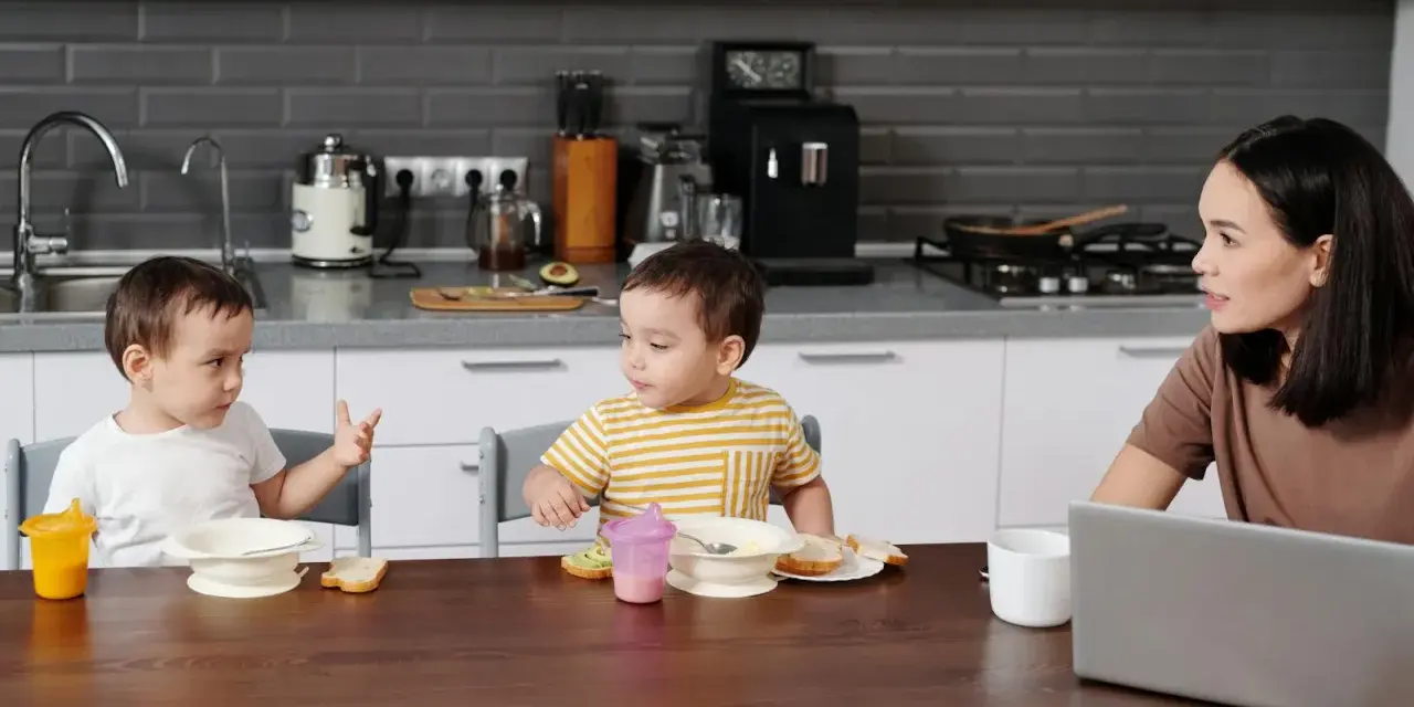 Mama słucha, jak dziecko zaczyna mówić pierwsze zdania, podczas wspólnego posiłku w kuchni.