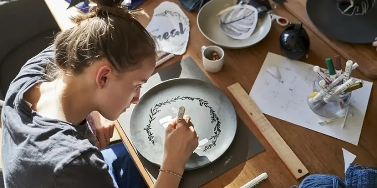 Dziewczyna maluje wzór na talerzu, tworząc własny przepis na masę porcelanową.