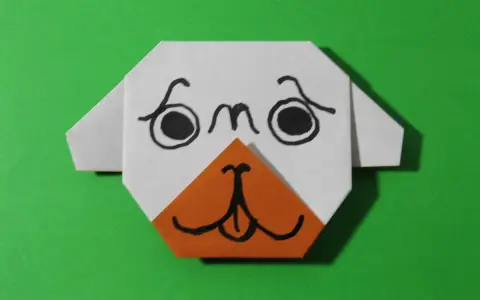 Urocza praca plastyczna: origami przedstawiające pyszczek psa z czarnymi oczami i pomarańczowym noskiem.