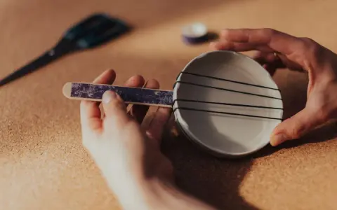 Ręce składają proste instrumenty muzyczne do zrobienia: miseczkę z gumkami i patyczek.