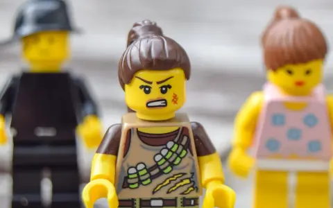 Trzy ludziki Lego. Jeden z nich, w brązowym stroju, ma zaciętą minę, co sugeruje nieradzenie sobie z emocjami.