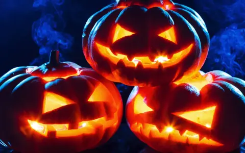 Trzy świecące **jack o lantern** z wyciętymi strasznymi minami, otoczone niebieską mgłą, tworzą mroczny, halloweenowy nastrój.