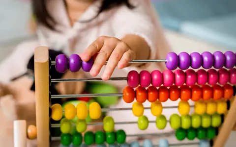 Dziecko bawi się kolorowymi liczydłami, ucząc się liczyć. To świetna zabawa edukacyjna!