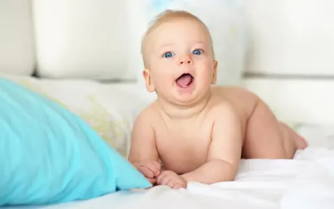 Niebieskooki bobas na brzuchu, kiedy dziecko głuży, z otwartymi ustami i radosnym wyrazem twarzy.