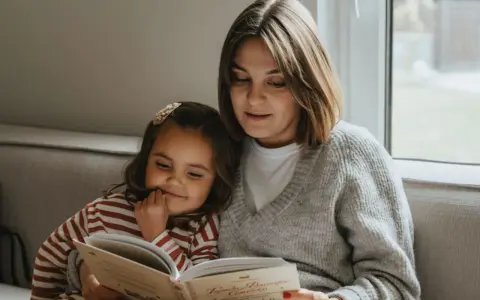 Mama czyta dziecku bajkę, pokazując, jak zachęcić dziecko do czytania. Wspólne chwile z książką budują więź i rozwijają wyobraźnię.
