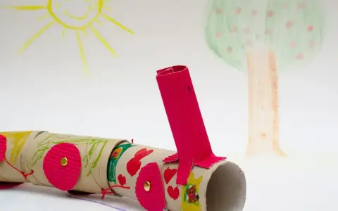 Kolorowy pociąg z rolek po papierze toaletowym, wykonany z rzeczy z recyklingu dla dzieci. W tle rysunek słońca i drzewa.