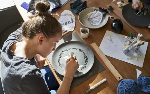 Dziewczyna maluje wzór na talerzu, tworząc własny przepis na masę porcelanową.