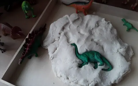 Zabawy z masą plastyczną i figurkami dinozaurów to świetne pomysły na dzień dinozaura. Dzieci mogą tworzyć prehistoryczne krajobrazy.