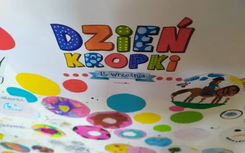 Kolorowa praca plastyczna na Dzień Kropki. Litery "Dzień Kropki" ozdobione kropkami, poniżej rysunki dzieci: konik z jeźdźcem, bałwanek i kolorowe kropki.