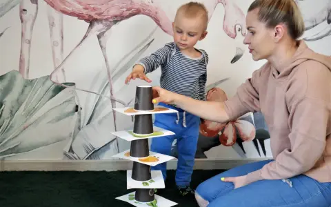 Mama i synek budują wieżę z kubeczków, ćwicząc naukę angielskiego dla 4 latka.
