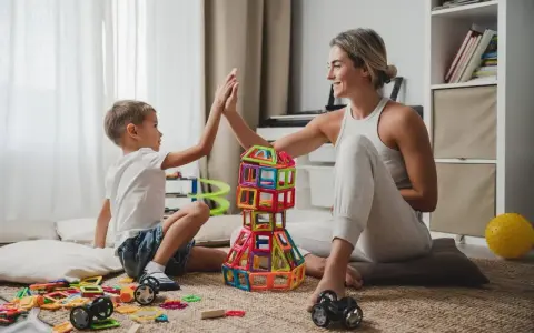 Mama i syn świętują sukces budowli z klocków magnetycznych. To świetne kreatywne zabawy dla 8 latka, rozwijające wyobraźnię i zdolności manualne.