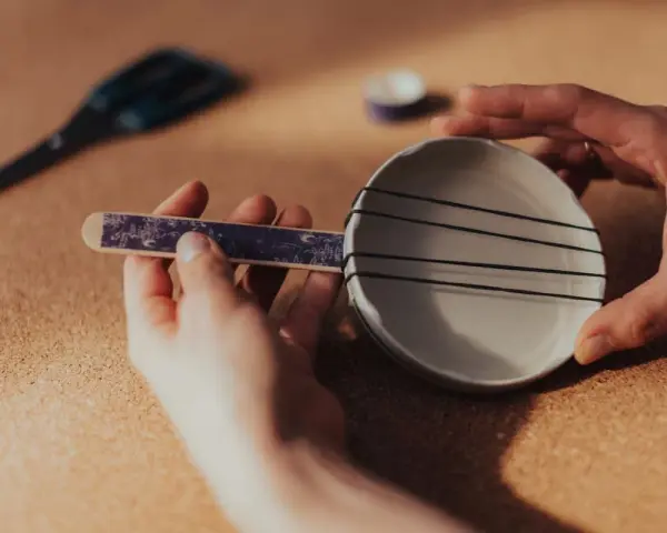 Ręce składają proste instrumenty muzyczne do zrobienia: miseczkę z gumkami i patyczek.