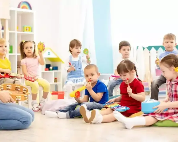 Wesołe zabawy w przedszkolu: dzieci grają na instrumentach, śpiewają i bawią się z nauczycielem.