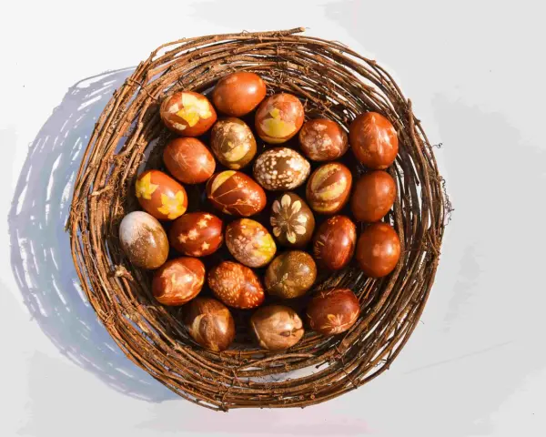 Wielkanocne pisanki w koszyku z gałęzi, barwione w łuskach cebuli, z naturalnymi wzorami liści i kwiatów.