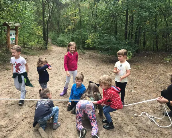 Dzieci biorą udział w leśnej grze terenowej, przeciągając linę.
