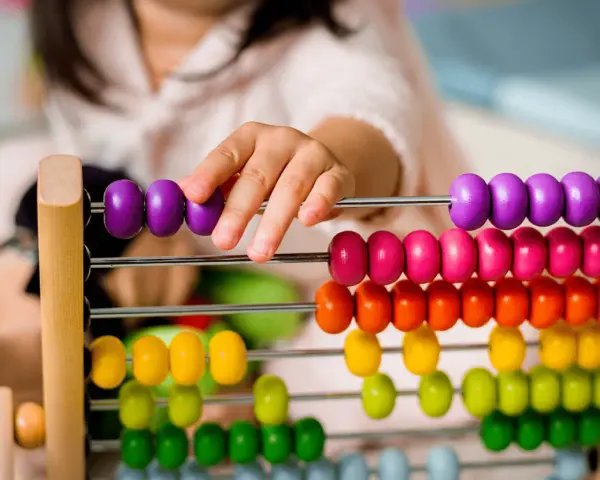 Dziecko bawi się kolorowymi liczydłami, ucząc się liczyć. To świetna zabawa edukacyjna!
