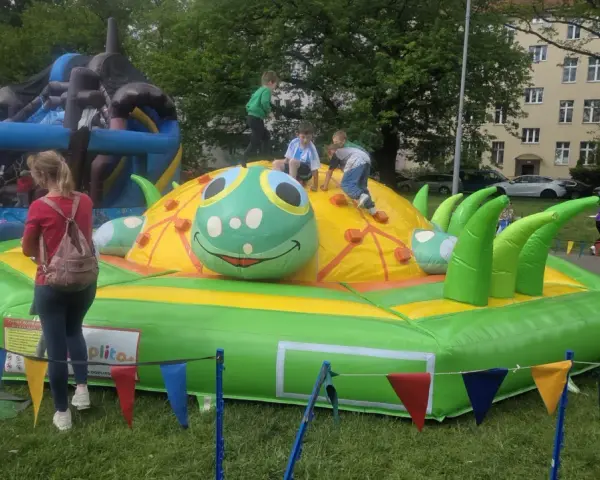 Dzieci bawią się na dmuchanej gąsienicy, która jest jedną z atrakcji na dzień dziecka.