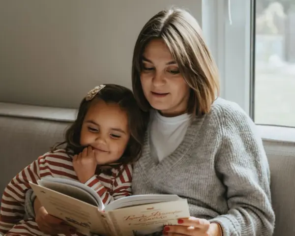 Mama czyta dziecku bajkę, pokazując, jak zachęcić dziecko do czytania. Wspólne chwile z książką budują więź i rozwijają wyobraźnię.
