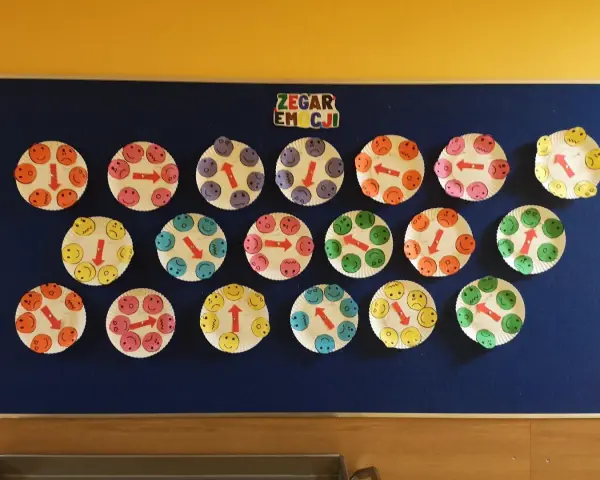 Praca plastyczna dla 3 latków: zegar emocji z uśmiechniętymi buźkami na talerzykach papierowych.