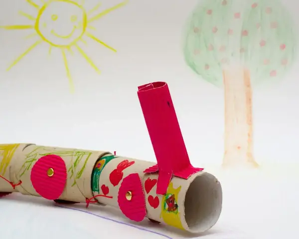 Kolorowy pociąg z rolek po papierze toaletowym, wykonany z rzeczy z recyklingu dla dzieci. W tle rysunek słońca i drzewa.
