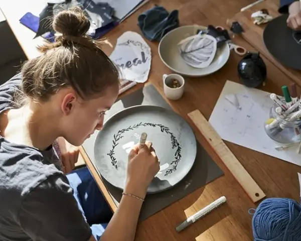 Dziewczyna maluje wzór na talerzu, tworząc własny przepis na masę porcelanową.