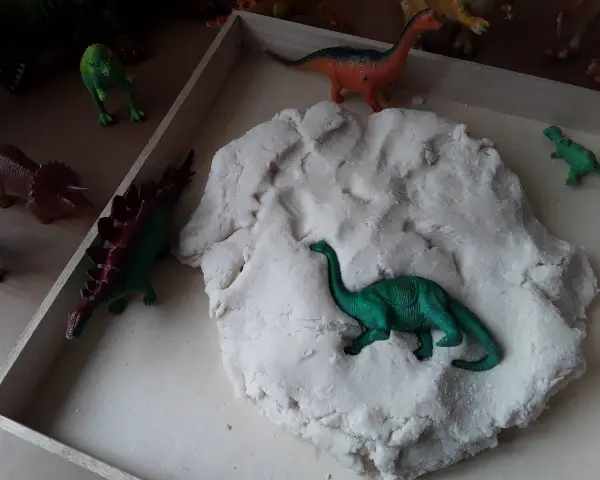 Zabawy z masą plastyczną i figurkami dinozaurów to świetne pomysły na dzień dinozaura. Dzieci mogą tworzyć prehistoryczne krajobrazy.