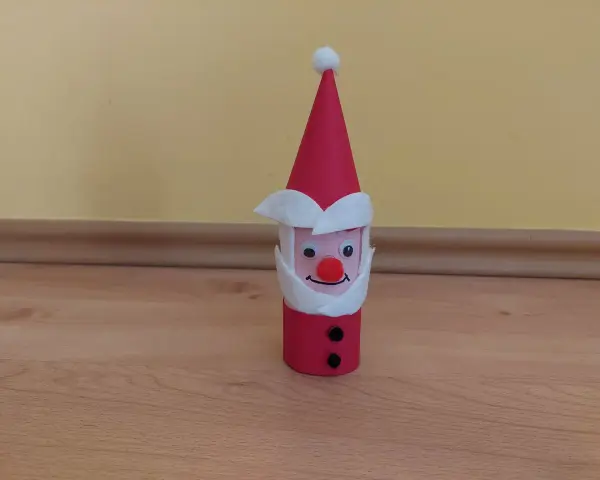 Urocza praca plastyczna Mikołaj z rolki papieru, z czerwonym noskiem i czarnymi guzikami.