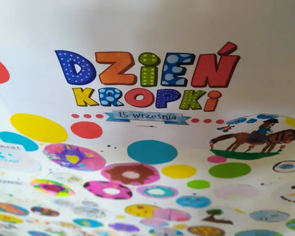 Kolorowa praca plastyczna na Dzień Kropki. Litery "Dzień Kropki" ozdobione kropkami, poniżej rysunki dzieci: konik z jeźdźcem, bałwanek i kolorowe kropki.