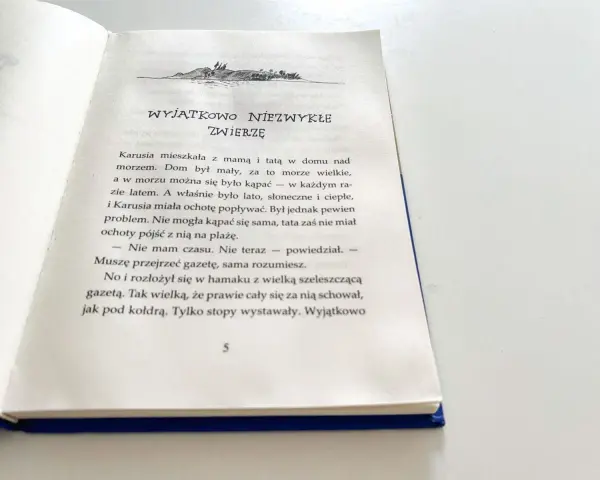 Piaskowy wilk bohaterowie: Karusia i tata nad morzem. Tata czyta gazetę, a Karusia chce popływać.