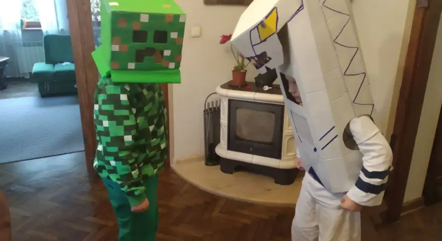 Dzieci w łatwych przebraniach z bajek: jeden w stroju Creepera z Minecrafta, drugi jako robot z kartonu.